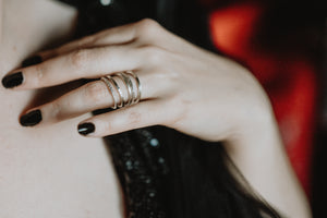 Close up of a woman’s hand wearing silver dainty stacking rings