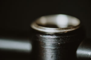 Smooth triangle dainty silver stackable ring on a display stand